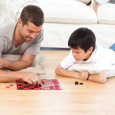 Photo of a volunteer playing checkers with a young man