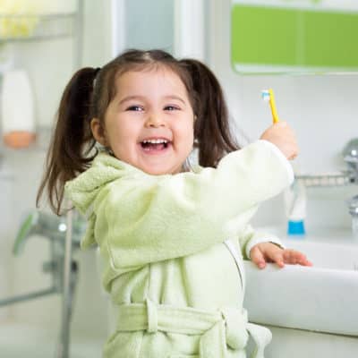 Photo of a young girl smiling while holding a toothbursh