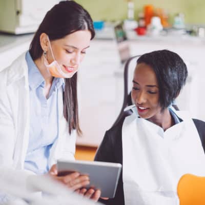 Photo of a young woman sitting in a dentist chair looking at her results