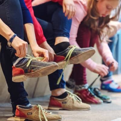 Photo of a group of people lacing up bowling shoes