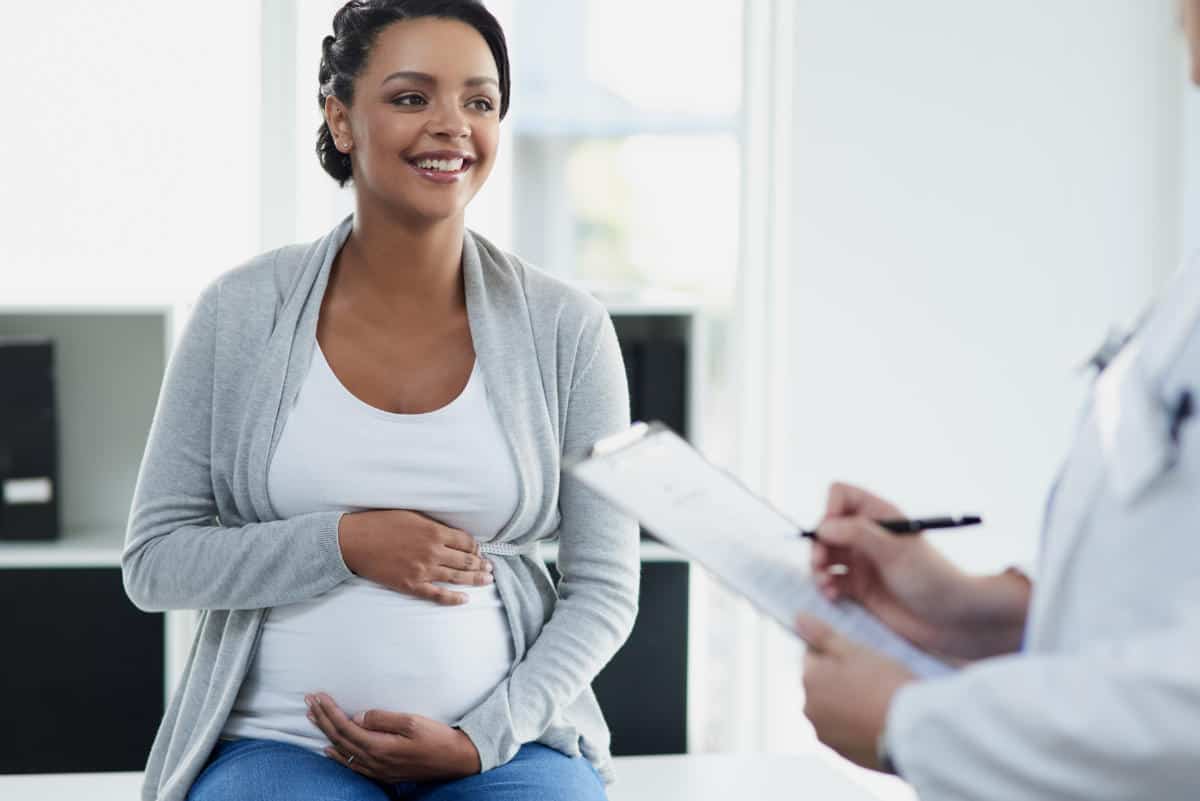 Photo of a woman holding her pregnant belly and smiling