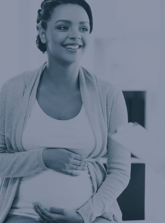 Photo of a pregnant woman holding her belly and smiling