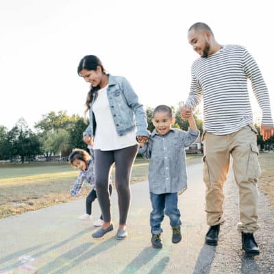 Photo of a family holding hands while walking in a park