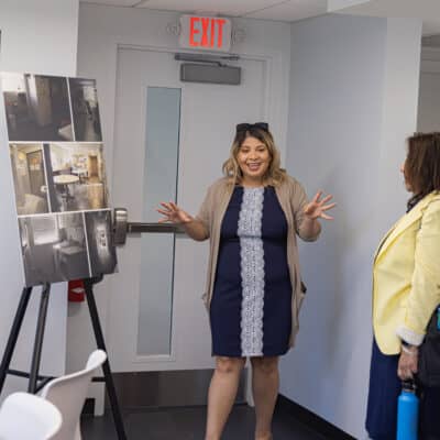 PCH Staff Member stands near a presentation board of photos representing pre construction