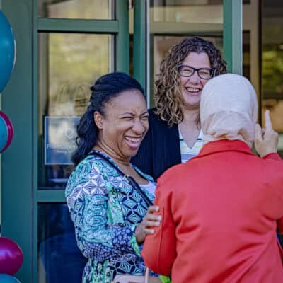 Three woman standing in front of windows laughing