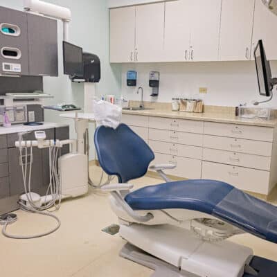 Spacious dental exam room with a lounge style dental chair surrounded by cabinets