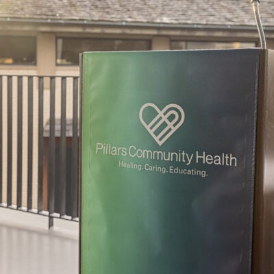 podium with a gradient banner featuring the Pillars Community Health logo