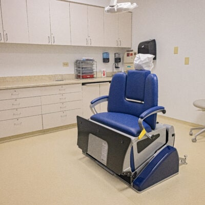 Spacious Dental Suite with a wheelchair accessible dental chair in the upright position surrounded by open space and a wall of cabinetry