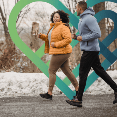 Two people running on pavement in a snow covered landscape