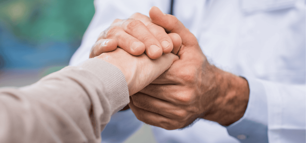 Doctor holding a patient’s hand, offering compassionate medication‑assisted recovery support at Pillars Community Health.
