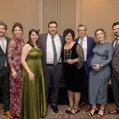 Angela Curran stands with family members while holding the Power of One Award during the All In for PCH Gala.