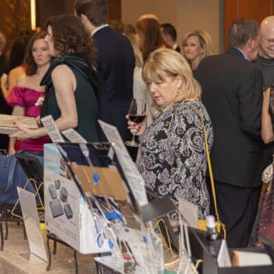 Guests browse silent auction items displayed on tables during the All In for PCH Gala.
