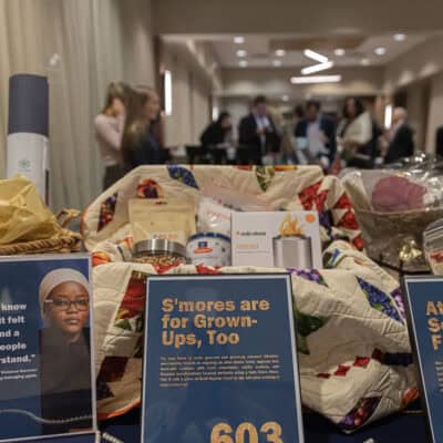 Silent auction display featuring gift baskets, a quilt, and items arranged on a table during the All In for PCH Gala.