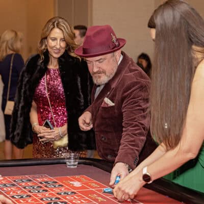 Dr. Eric Spratford places chips on a roulette table while guests look on during casino entertainment at the All In for PCH Gala.