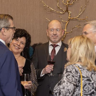 Kris Curran, Angela Curran, and guests share a conversation while holding drinks during the gala reception.