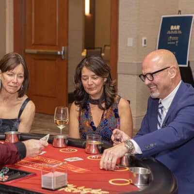 Guests play cards and place chips at a casino table during the All In for PCH Gala.
