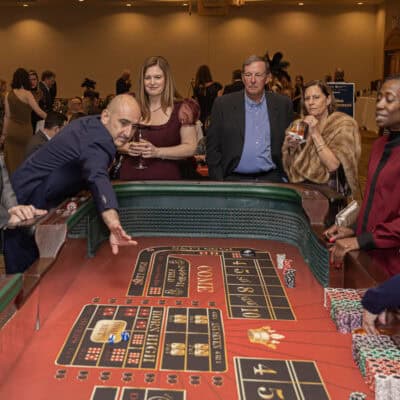 Guests gather around a craps table watching as a player rolls the dice during casino entertainment at the gala.