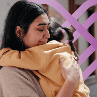Dark Haired Woman hugging child with purple PCH logo in the background